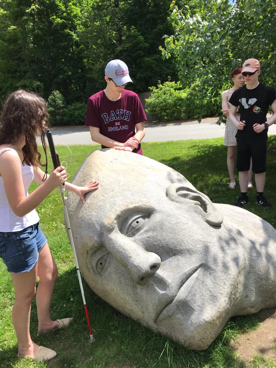 students touching a stone sculpture.