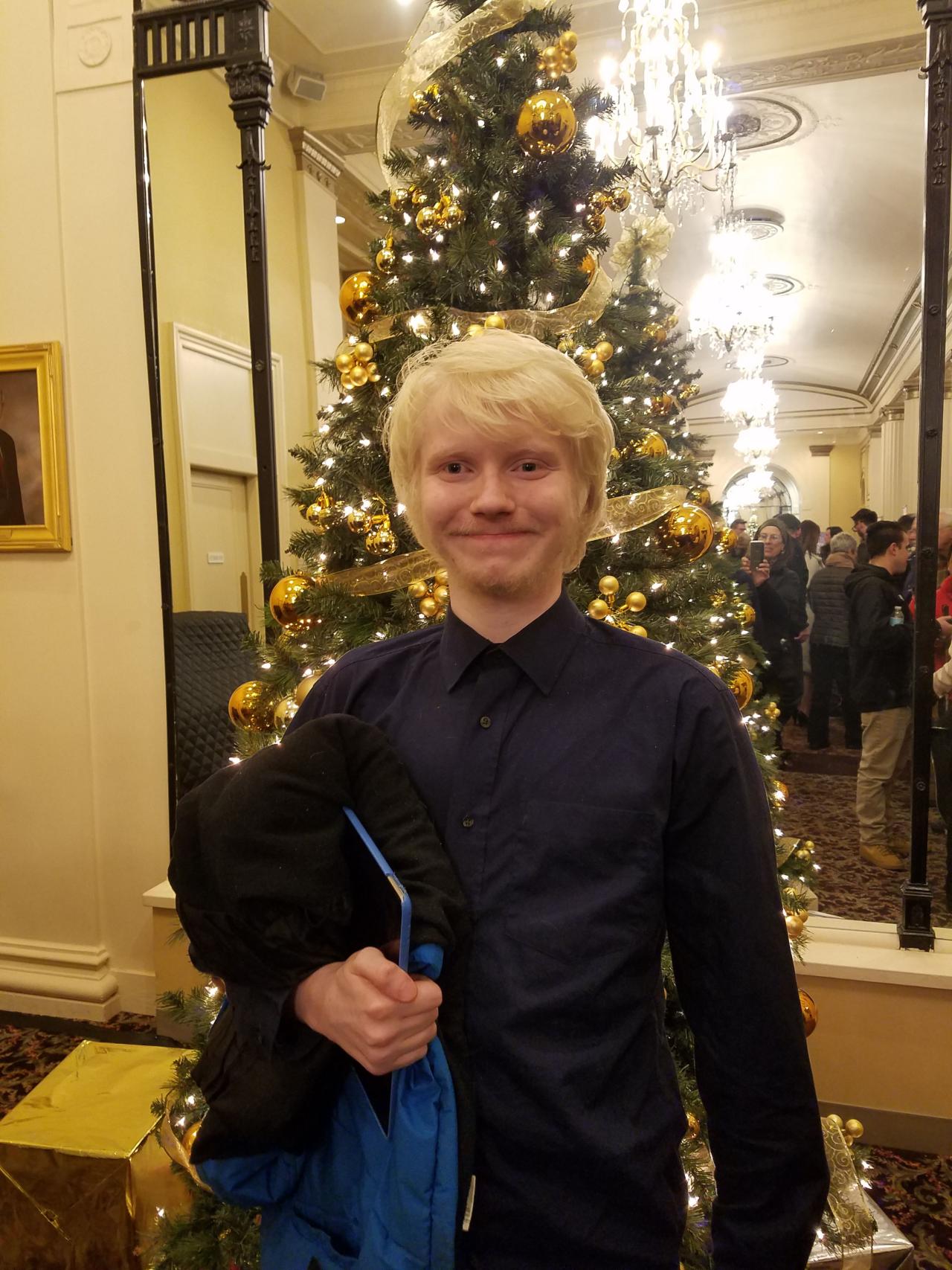 young man with blond hair smiling and holding a show booklet at the Hanover Theater.