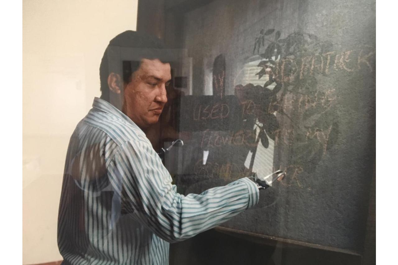 Man with prosthetic hands writing on chalkboard