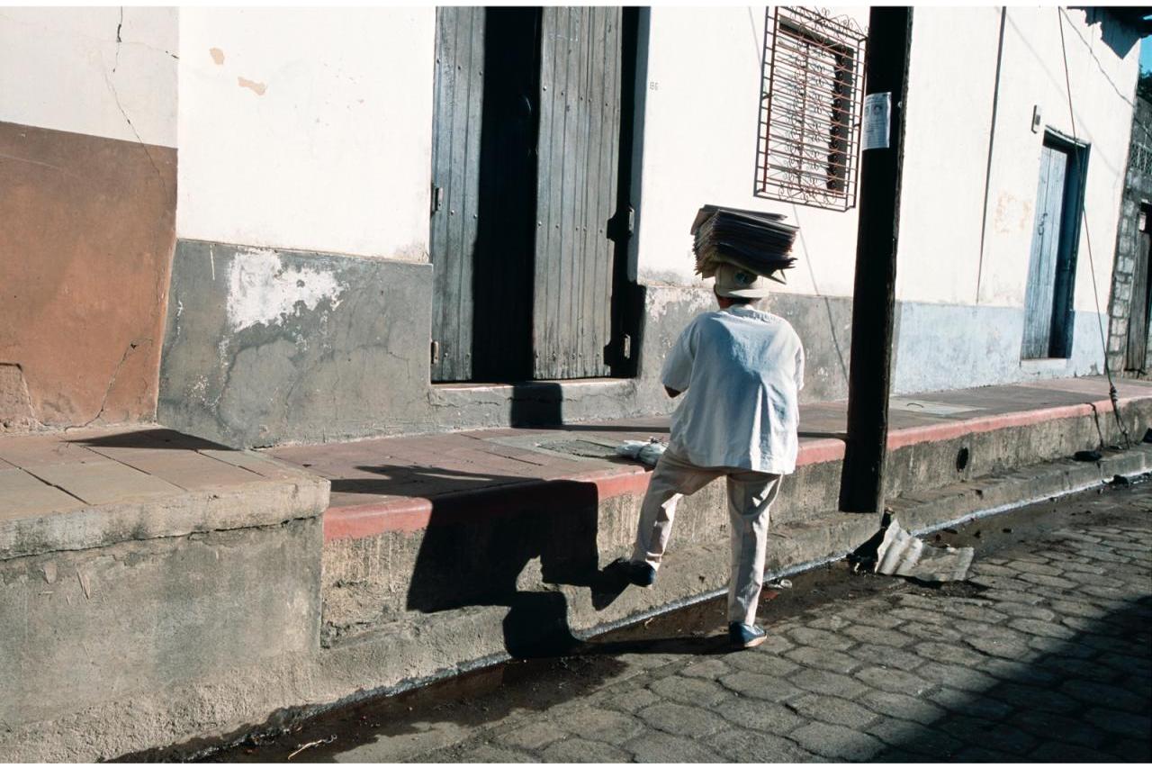 Man walking up steep steps in Leon, Nicaragua carrying newspapers on his head. (photo by Stephen Petegorsky)