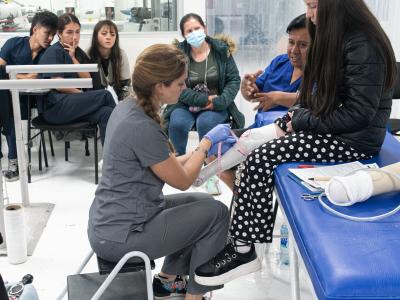 Polus Center Board President, Nellie Zarif, fitting a young girl with a prosthetic leg in a clinic in Colombia.