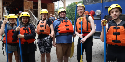 Students in life vests post for a group photo at a whitewater rafting event